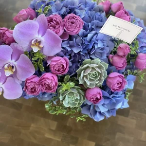 Flower arrangement with orchid and succulents in a glass square vase